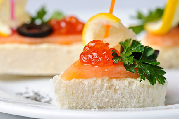 Fresh red caviar on bread sandwiches on the plate. Tartlets with red caviar on the background.