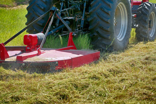 Mowing Large red modern tractor mows the grass on the field tractor mowing stock pictures, royalty-free photos & images
