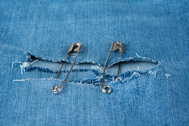 istock Hole in blue jeans fixed with safety pins. 921226060