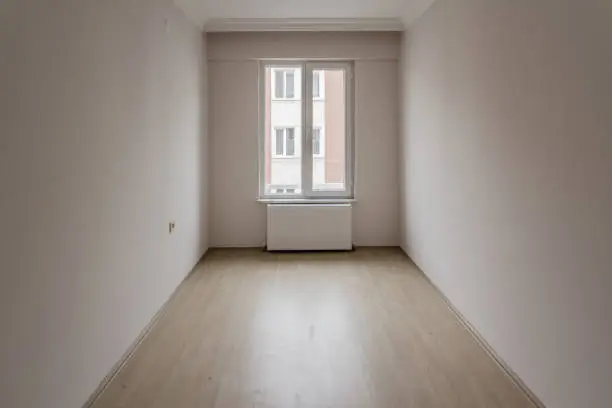 Bright small empty room of new apartment with one window and parquet  floor