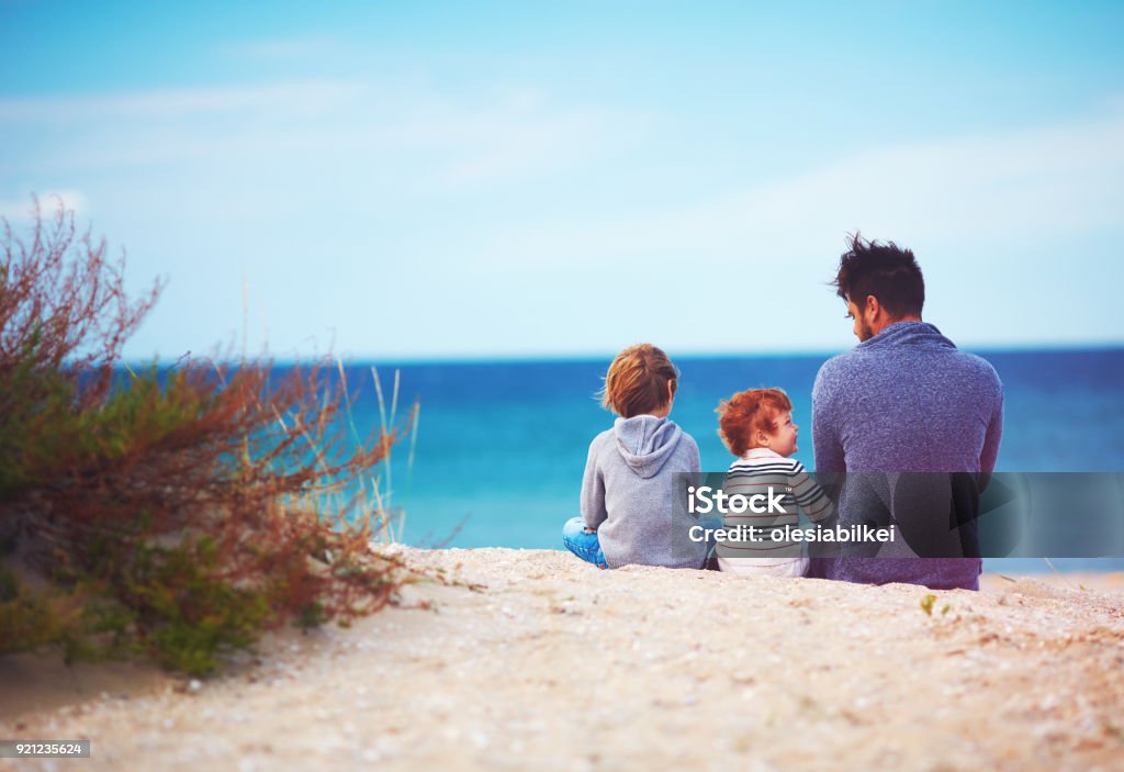 padre e hijos en la playa de arena cerca del mar en día de viento - Foto de stock de Padre libre de derechos