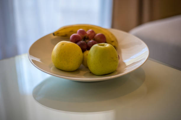 Healthy fruit and vegetables snacks on a white plate. Grapes and walnuts with slice apples, strawberries and carrots and kohlrabi. Selective focus.