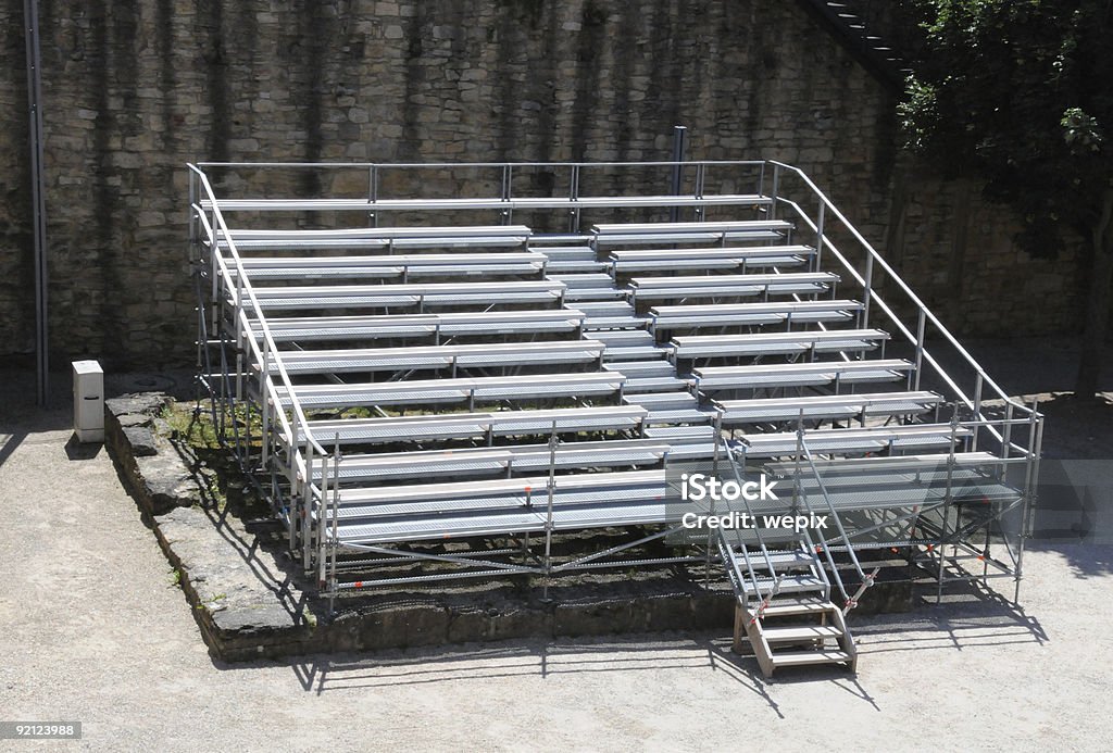 Metal bleachers old citadel courtyard bright summer sunlight Metal bleachers in an old citadel courtyard waiting for the audience of a summer open air movie, theater performance or a concert. Horizontal orientation. Bench Stock Photo