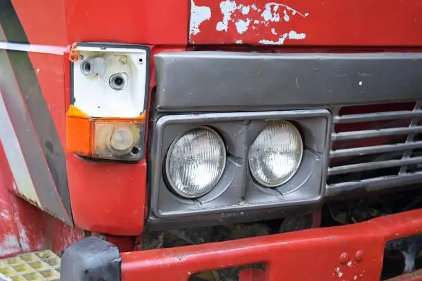 Shot on headlights and broken blinker in abandoned red truck.