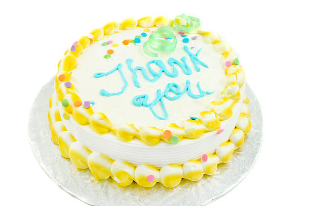 yellow and white frosted festive cake with thank you written in blue