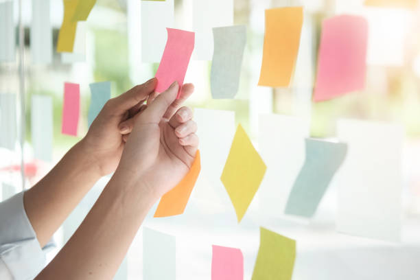 istock Creative business people reading sticky notes on glass wall with colleague working use post it notes to share idea discussing and teamwork, brainstorming concept.Closeup shot. 921248232