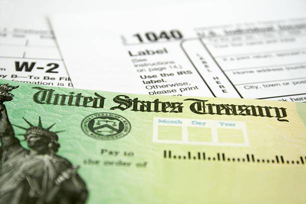 Income tax refund check on tax forms Tax Refund Check with W-2 and 1040 U.S. Individual Income Tax Return Forms refund stock pictures, royalty-free photos & images