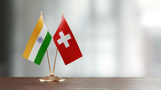 Indian And Swiss Flag Pair On A Desk Over Defocused Background