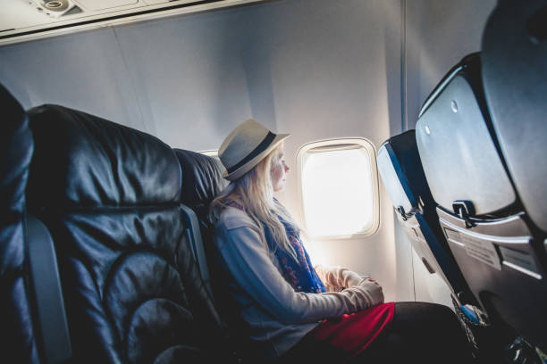 istock Young Woman Alone Looking Outside and Sitting inside Airplane 921280420