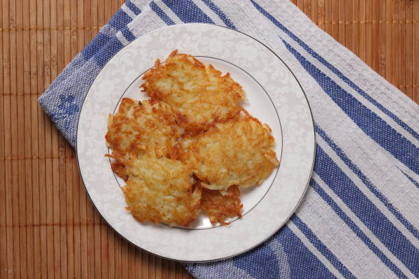 Potato pancakes with sour cream and lettuce, potato pancakes on a plate, bamboo background, homemade cuisine, cooked potato pancakes for dinner on a holiday, retro style