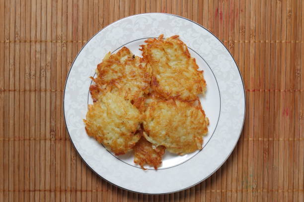 Potato pancakes with sour cream and lettuce, potato pancakes on a plate, bamboo background, homemade cuisine, cooked potato pancakes for dinner on a holiday, retro style