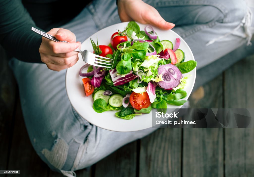 Fresh salad in hands view from above Fresh salad in the hands of the girl from above, the concept of healthy food and veggie Eating Stock Photo