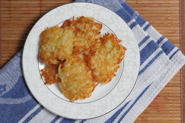 Potato pancakes with sour cream and lettuce, potato pancakes on a plate, bamboo background, homemade cuisine, cooked potato pancakes for dinner on a holiday, retro style