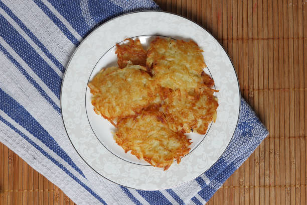 Potato pancakes with sour cream and lettuce, potato pancakes on a plate, bamboo background, homemade cuisine, cooked potato pancakes for dinner on a holiday, retro style