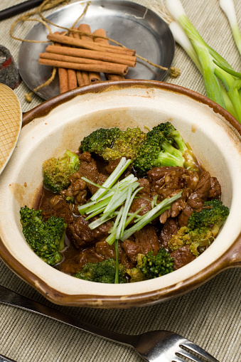 Beef stew with potato, carrot and herbs in a skillet. Black background. Top view.