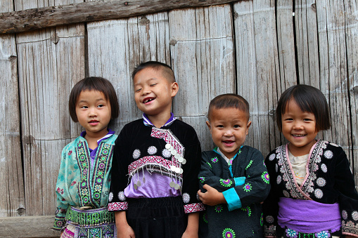 A group of hill tribe children standing in front of a bamboo wall. Location: Doi Suthep, Chiang Mai, Thailand