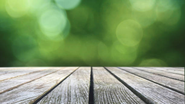 Rustic Wood Table Over Green Blurred Background Rustic Wood Table Texture Over Green Spring Nature Blurred Background, Horizontal fall picnic table stock pictures, royalty-free photos & images
