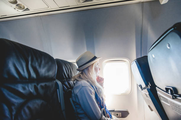 istock Young Woman Alone Looking Outside and Sitting inside Airplane 921309454