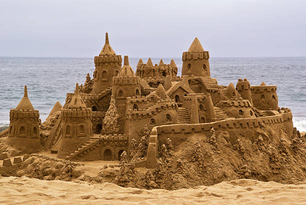 замок из песка на пляже, с видом на океан в заднем плане. - sandcastle стоковые фото и изображения