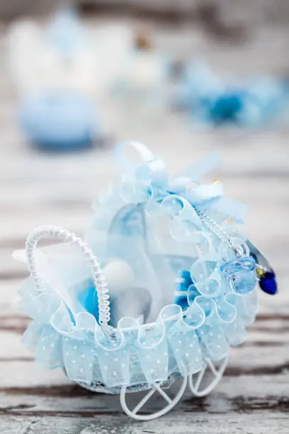 Blue toy baby carriage prepared as a gift for baby shower on white wooden background