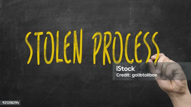 Hand Writing Stolen Process With Marker Against Blackboard Stock Photo - Download Image Now