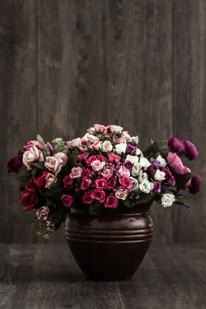 Artificial colorful flowers in a brown flower vase with copy space