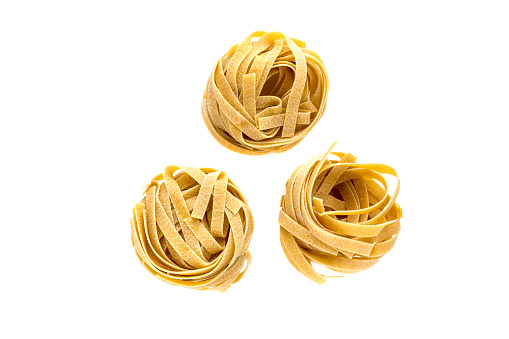 Macaroni nests on a white background. Macaroni tagliatelle close-up on a white background.