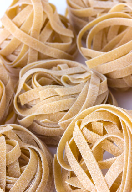 istock Macaroni nest close-up on a white surface. Tagliatelle macaroni lie a bunch next to each other. 921335172
