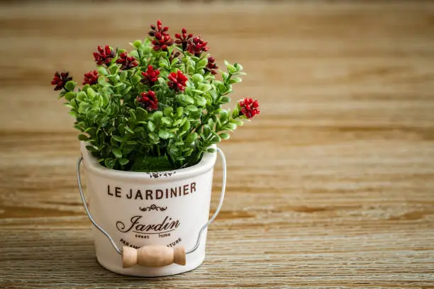 Artificial red flower in white pots on wooden background