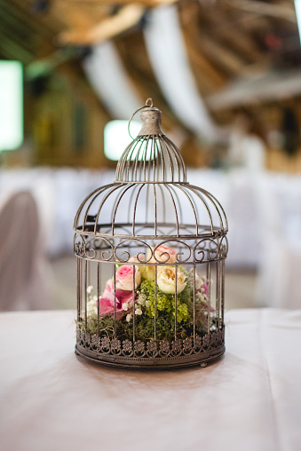 Birdcage with pink and yellow roses; decoration for a wedding party