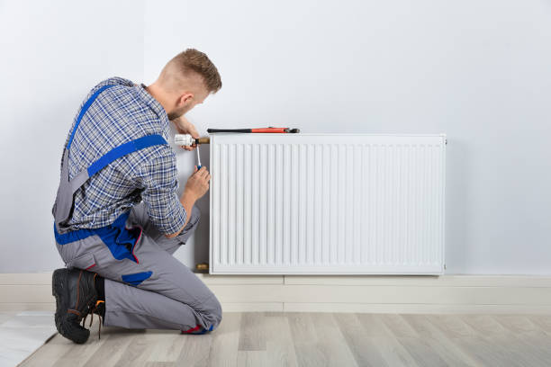 Male Plumber Fixing Thermostat Rear View Of Male Plumber Fixing Thermostat With Screwdriver And Wrench On Radiator home heating stock pictures, royalty-free photos & images