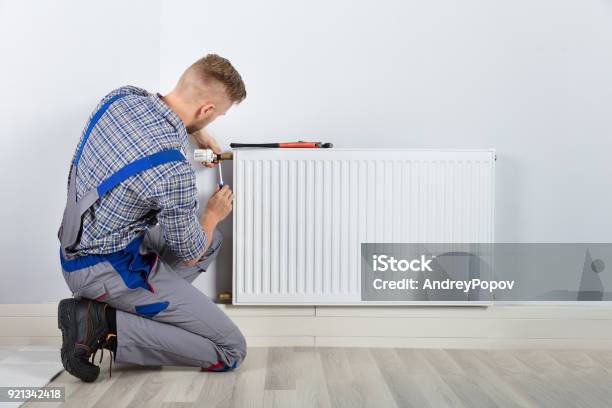 Male Plumber Fixing Thermostat Stock Photo - Download Image Now - Radiator - Heater, Home Heating, Repairing