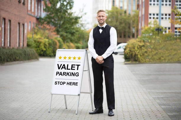 Young Male Valet Standing Near Valet Parking Sign Portrait Of A Smiling Young Male Valet Standing Near Valet Parking Sign chauffeur standing stock pictures, royalty-free photos & images