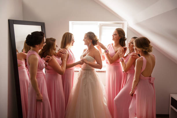 Bride with bridesmaids posing in hotel or fitting room at wedding day Bride with bridesmaids posing in hotel or fitting room at wedding day wedding dress photos stock pictures, royalty-free photos & images