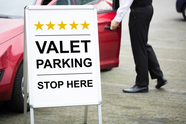 young male valet standing near valet parking sign - valet parking imagens e fotografias de stock