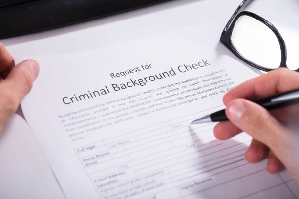 istock Person Hand Filling Criminal Background Check Application Form 921342970