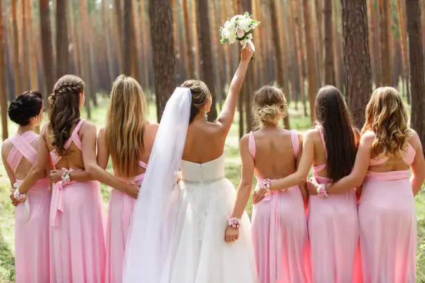 Bride and bridesmaids in pink dresses having fun at wedding day. Happy marriage and wedding party concept