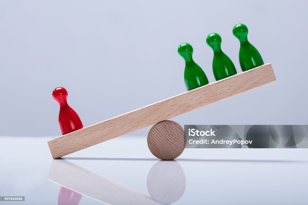 Pawns Figures On Wooden Seesaw Red And Green Pawns Figures Balancing On Wooden Seesaw Over The Desk Imbalance Stock Photo