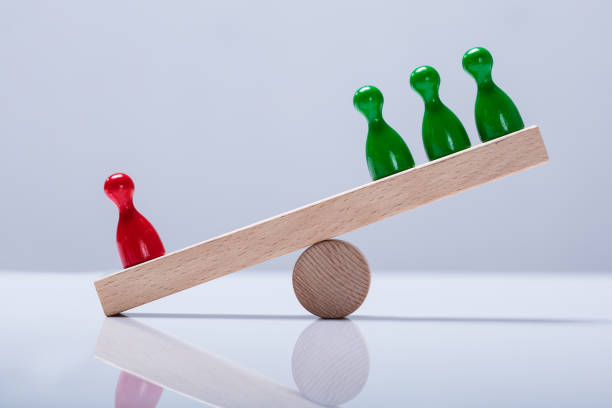 Pawns Figures On Wooden Seesaw Red And Green Pawns Figures Balancing On Wooden Seesaw Over The Desk pawn chess piece photos stock pictures, royalty-free photos & images
