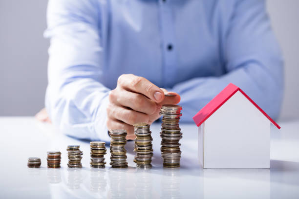 istock Increased Stack Of Coins In Front Of House Model 921345634