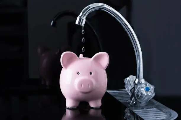 Dripping Water Droplets Are Falling In The Pink Piggybank From Kitchen Sink Faucet