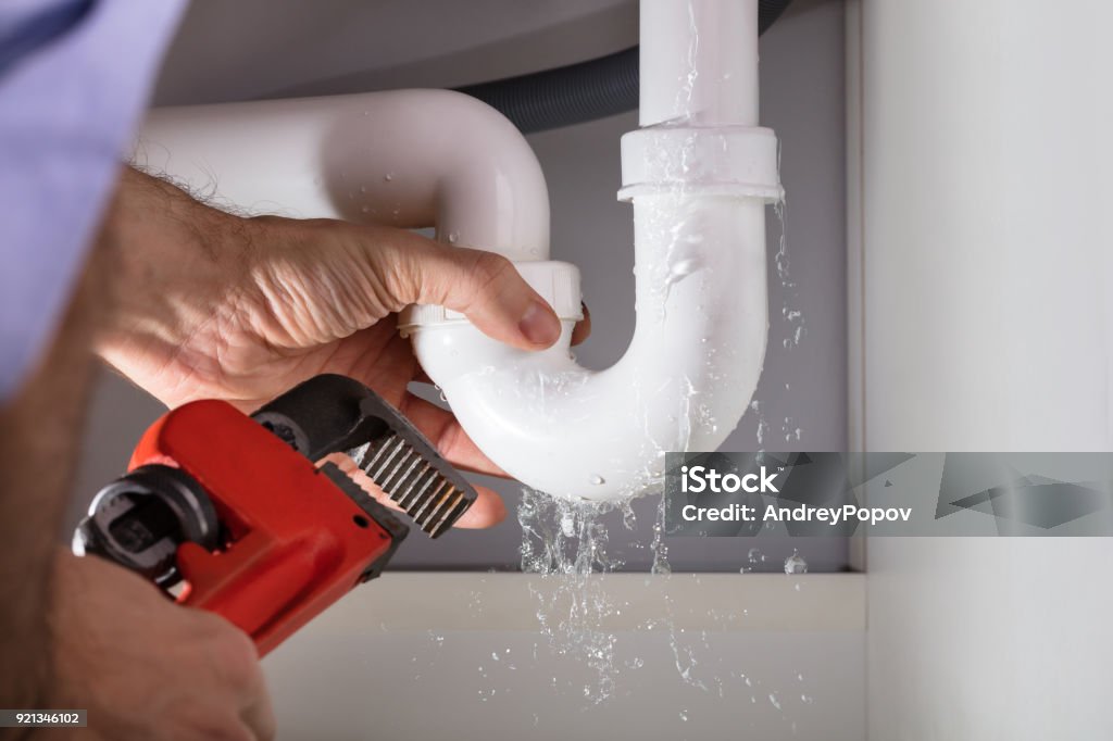 Plumber Fixing Sink Pipe With Adjustable Wrench Close-up Of Male Plumber Fixing White Sink Pipe With Adjustable Wrench Plumber Stock Photo