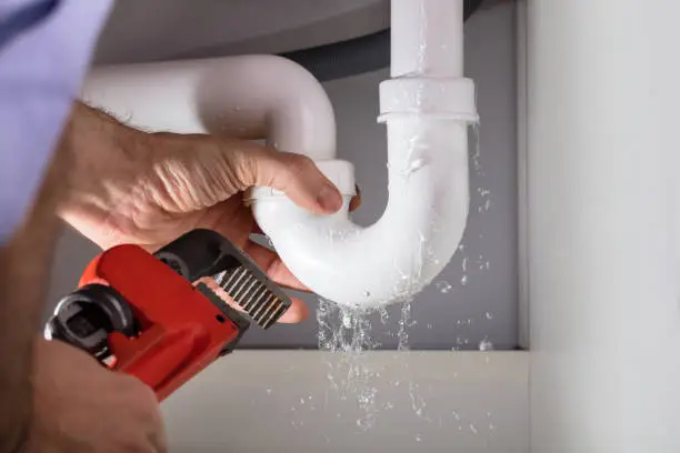 Photo of Plumber Fixing Sink Pipe With Adjustable Wrench