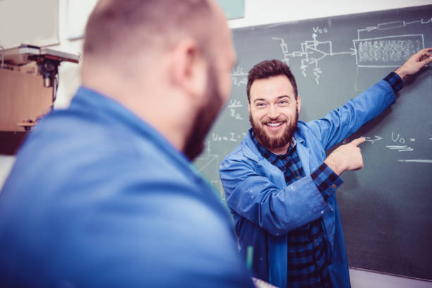 zwei lächelnde ingenieure diskutieren über problem im büro - confusion mathematics student mathematical symbol stock-fotos und bilder