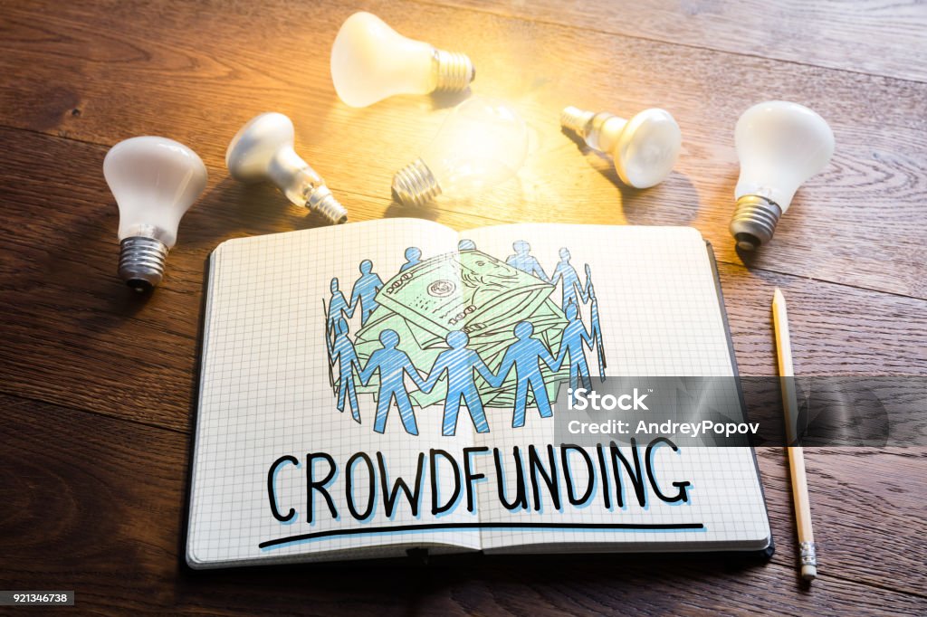 Crowdfunding Concept Crowdfunding Concept In Notepad Near Glowing Lightbulbs Crowdfunding Stock Photo
