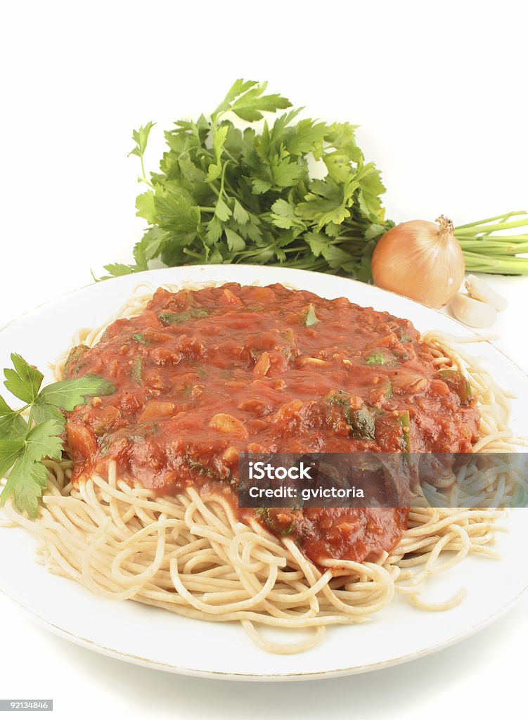 spaghetti dinner whole wheat spaghetti with vegetable sauce with garlic,onion, and parsley in the background Color Image Stock Photo