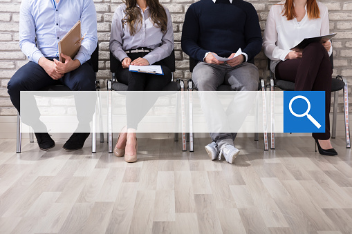 Close-up Of Business People Sitting On Chair Waiting For Job Interview In Office