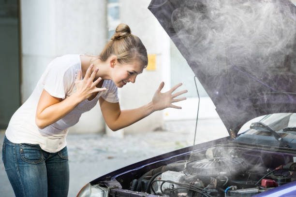 Frustrated Woman Looking At Broken Down Car Engine Frustrated young woman looking at broken down car engine on street overheated photos stock pictures, royalty-free photos & images