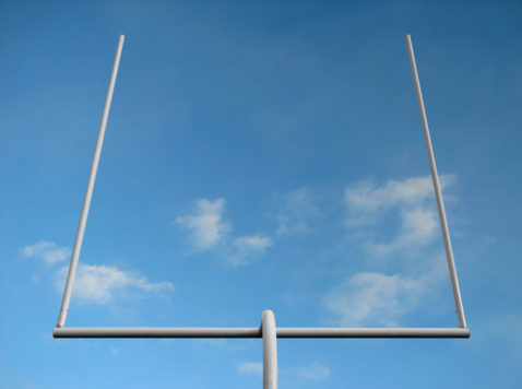 American football field goal posts against the blue sky.