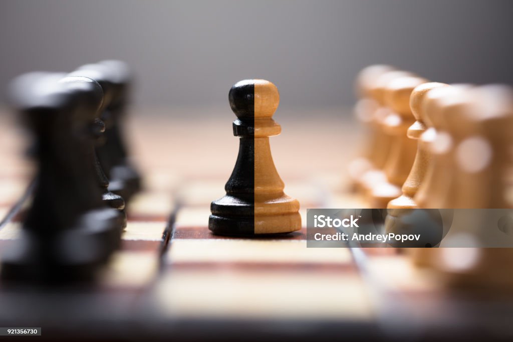 Double Color Pawn Amidst Other Chess Pieces On Board Closeup of double color pawn amidst other chess pieces on board game Mergers and Acquisitions Stock Photo